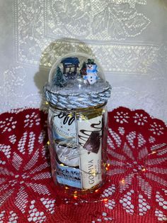 a glass jar filled with lots of different types of items on top of a red doily