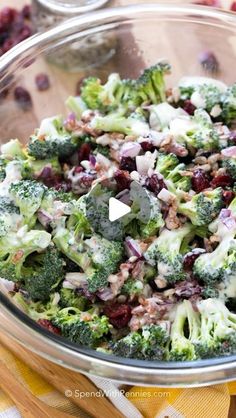 a bowl filled with broccoli and cranberries on top of a table