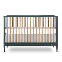 a baby crib with white sheets and wood trims on the bottom, in front of a white background