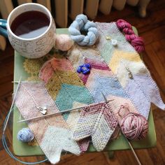 a table topped with yarn and crochet next to a cup of coffee