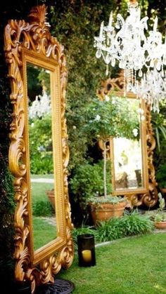 an ornate gold mirror sitting on top of a lush green field