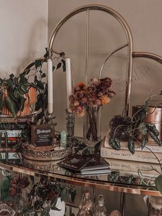 a shelf with books, candles and flowers on it