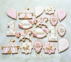 decorated cookies with pink and white icing are arranged on a table in front of a tent