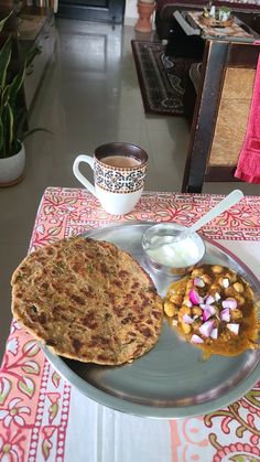 a plate with some food on it next to a cup of coffee and saucer