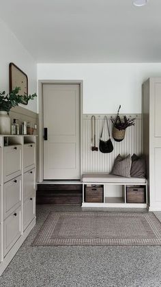 a room with white cabinets, drawers and a rug on the floor in front of it