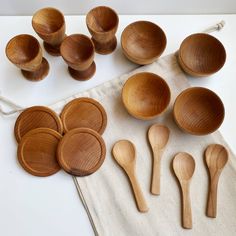 wooden spoons and bowls are sitting on a white tablecloth next to a tea towel