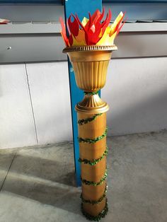 a tall golden vase with red and yellow flowers in it