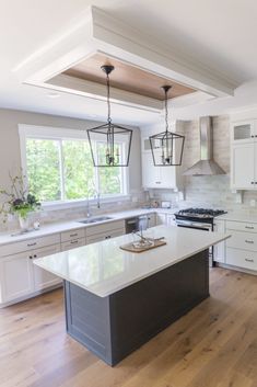 a large kitchen with an island in the middle and two lights hanging from the ceiling