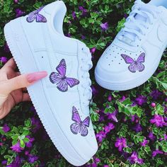 someone is holding their hand out to show off the purple butterflies on this nike air force