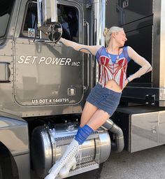 a woman standing on the back of a semi truck