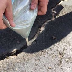 someone is holding something in their hand on the ground with dirt and cement behind them