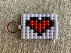 an object made out of plastic beads on the floor with a keychain attached to it