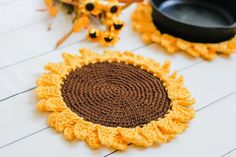 two crocheted sunflower coasters sitting next to each other on a table