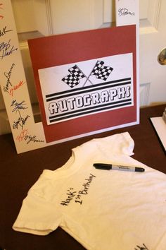 a t - shirt with autographs written on it next to a sign and pen