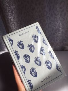 a person holding up a book with blue images on the front and back cover in their hand