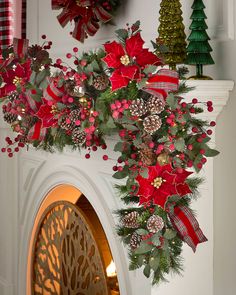 christmas decorations on the fireplace mantel with poinsettis and pine cones hanging from it