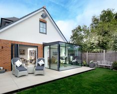 a white house with glass walls and patio furniture