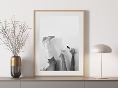 a black and white photo hanging on a wall next to a vase filled with flowers