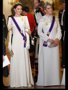 two women in white dresses and tiaras standing next to each other at an event