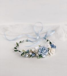 a blue and white flower crown on top of a bed next to a light blue ribbon