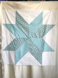 a blue and white quilt hanging on a wall