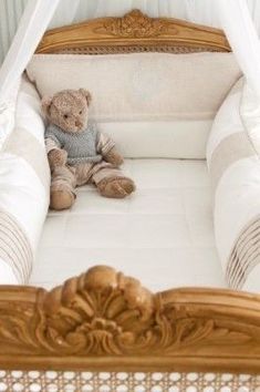 a teddy bear is sitting in a crib with white sheets and pillows on it