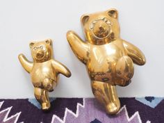 two gold colored teddy bears standing next to each other on a purple and blue rug