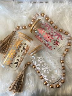 three glass jars with snowflakes and tassels on a white furnishing