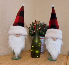 two gnomes are sitting next to a wine bottle on a table with christmas decorations