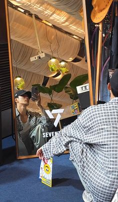 a man sitting on the ground in front of a mirror holding a bag and looking at his reflection