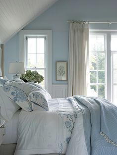 a bedroom with blue walls and white bedding