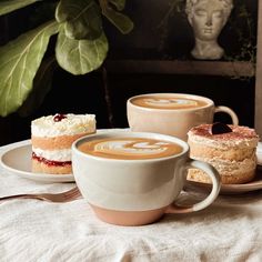 two cups of coffee sit on a table with pastries