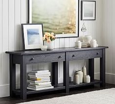 a black table with two drawers and some pictures on the wall next to it in front of a framed photograph