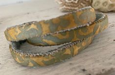 One (1) Hand made Fortuny fabric .25 inch stacking Bangle Bracelets in IMPERO No. 5077 . Color is Green and Gold  long staple Egyptian cotton  Last one! An upscale hand made one of a kind  rustic Fortuny fabric stacking Bangle Bracelet IMPERO is a classic Fortuny damask featuring blossoms and blooms. The fabric used for these bracelets is vintage taken from a set of draperies. It has a beautiful aged appearance and the gold metallic dye has softened to a deep bronze. Lined with an ultra soft luxurious stain resistant Scalamandre Silk Velvet in Seafoam.  Base is a made in USA solid Brass (nickle and lead free) flat Cuff blank.  Open or close for a perfect fit.  Measurements: .25  inches W X 6 inches L Fully adjustable Designed to fit  unisex adults and women/girls ages 14 and up  Great for Unique Patina Cuff Bangle Bracelet, Green Patina Cuff Bangle Bracelet, Unique Green Patina Cuff Bracelet, Gold-tone Oyster Bangle Bracelet, Vintage Patina Cuff Bracelet, Fortuny Fabric, Rustic Bracelet, Luxury Gifts For Her, Stacked Bangles