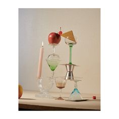 an assortment of wine goblets and glasses on a table with apples in the background