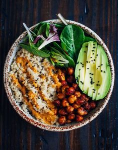 a bowl filled with rice, beans and avocado on top of a wooden table