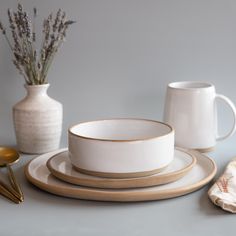 a table topped with plates and cups next to a vase