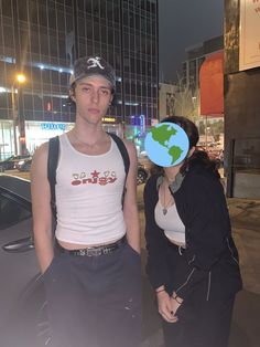 a man and woman standing next to each other in front of a building at night