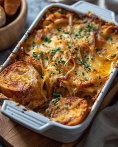 a casserole dish with cheese and onions on a cutting board next to bread