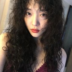 a woman with long curly hair is taking a selfie