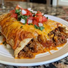 a white plate topped with a burrito covered in cheese and toppings on top of it