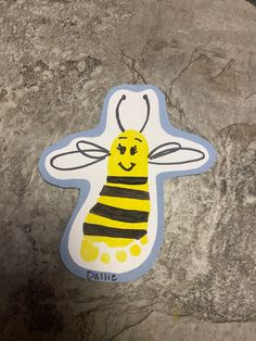 a yellow and black bee sticker sitting on top of a stone wall next to a rock