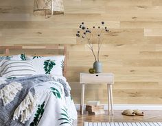 a bed room with a neatly made bed next to a night stand and wooden walls