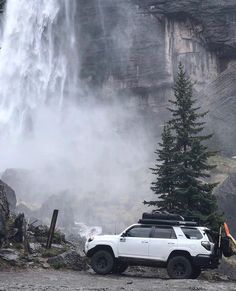 a white truck parked in front of a waterfall