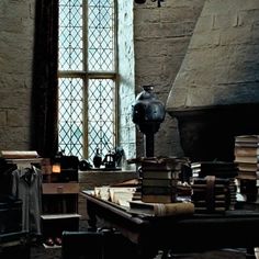 a room filled with lots of books next to a tall window and a lamp hanging from the ceiling