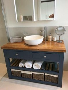 a bathroom with a sink, mirror and towels on the shelf in front of it