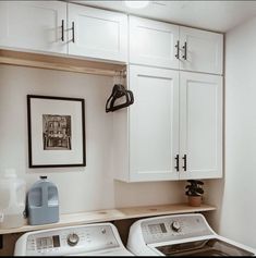 a washer and dryer sitting in a room next to cabinets with pictures on the wall