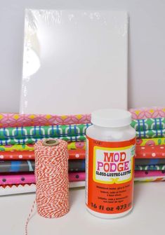 a spool of thread next to a bottle of mod podge glue on a table