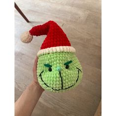 a hand holding a crocheted grin face ornament with a santa hat on