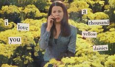 a woman talking on a cell phone in front of yellow flowers with words that say i love you